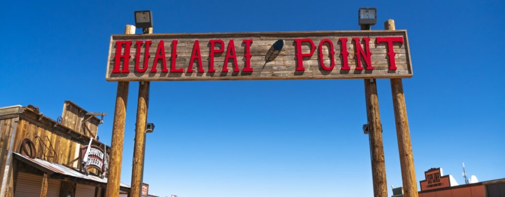 A wooden sign with "HUALAPAI POINT" in red letters hangs over a western-style building.
