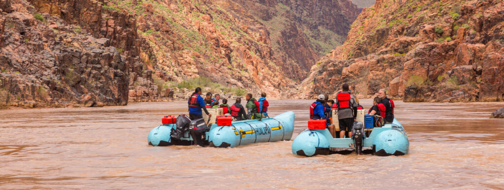 Two rafts with people in life vests river rafting in the Grand Canyon