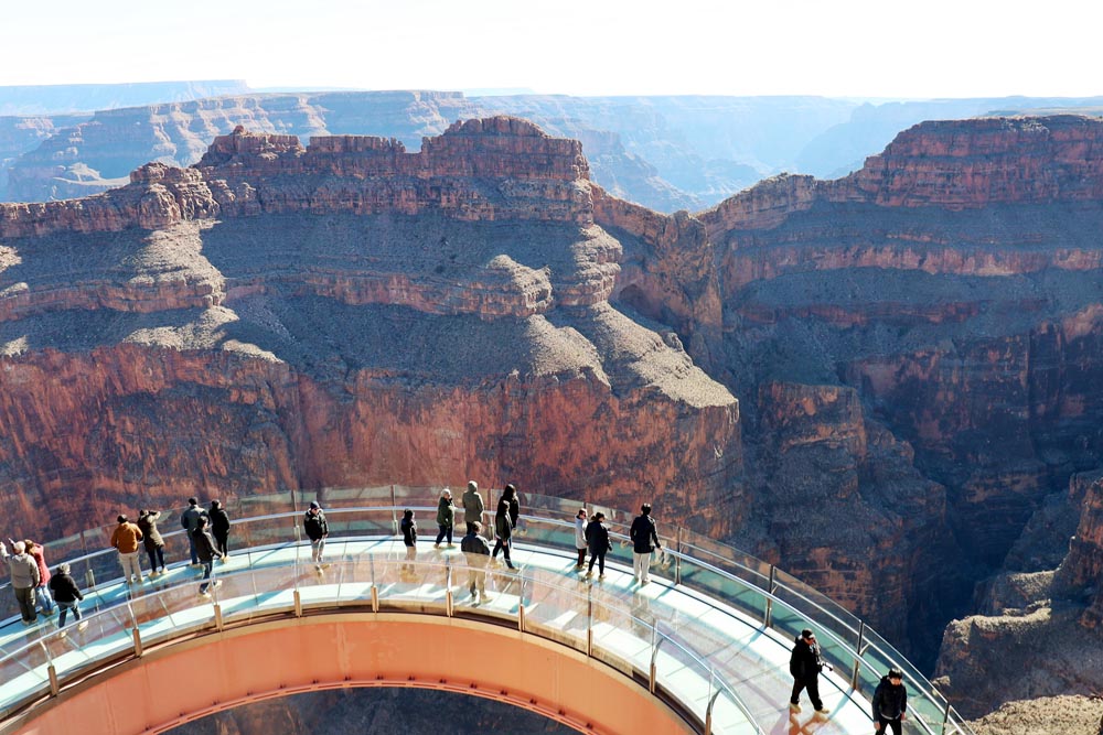 People walk on the glass Grand Canyon Skywalk, overlooking the vast canyon.