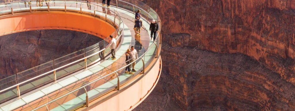 People walk on the glass Grand Canyon Skywalk over the canyon.