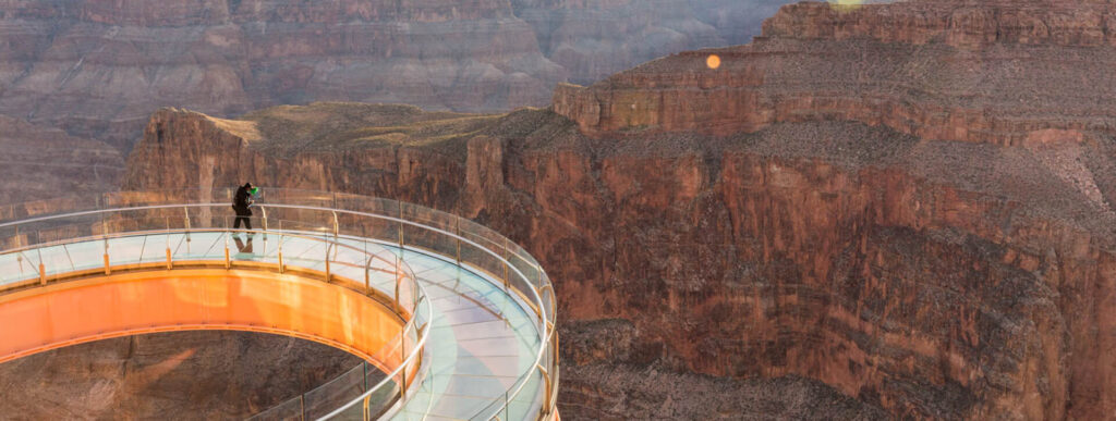 A person stands alone on the Grand Canyon Skywalk, looking out at the canyon.