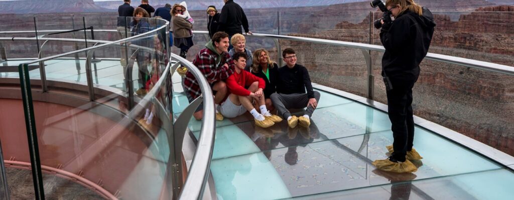 A group of people poses for a photo on the glass Grand Canyon Skywalk.